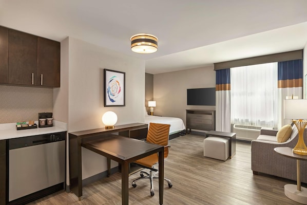 Une chambre d’hôtel équipée d’une kitchenette, d’un coin repas, d’un canapé, d’une télévision et d’une cheminée.