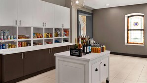 Een keukenhoek met witte kastjes, een minibar en een minibarbordje met de tekst 'Hilton Honors'.