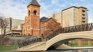 A bridge over a canal with a brick building and modern apartments in the background.