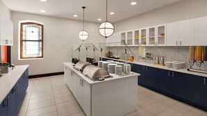 Een moderne keuken met een centraal eiland, witte kasten en een groot raam met glas-in-lood.