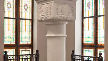 A white column with ornate carvings, flanked by two stained glass windows with colorful patterns.