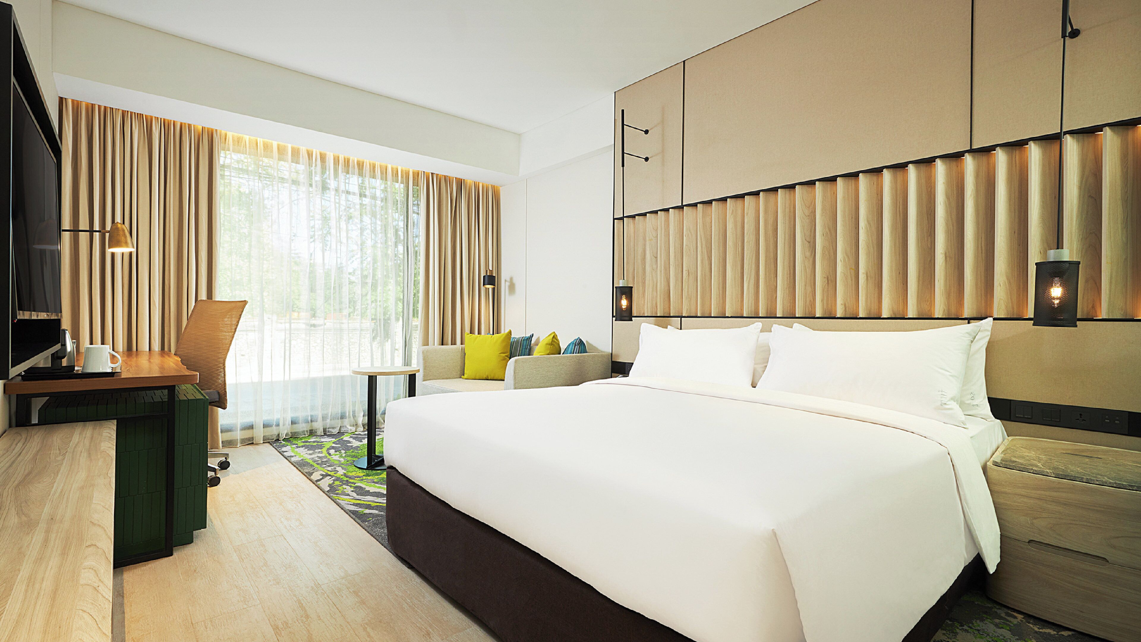 Una habitación de hotel con una cama grande, un escritorio con silla, un sofá y un televisor.