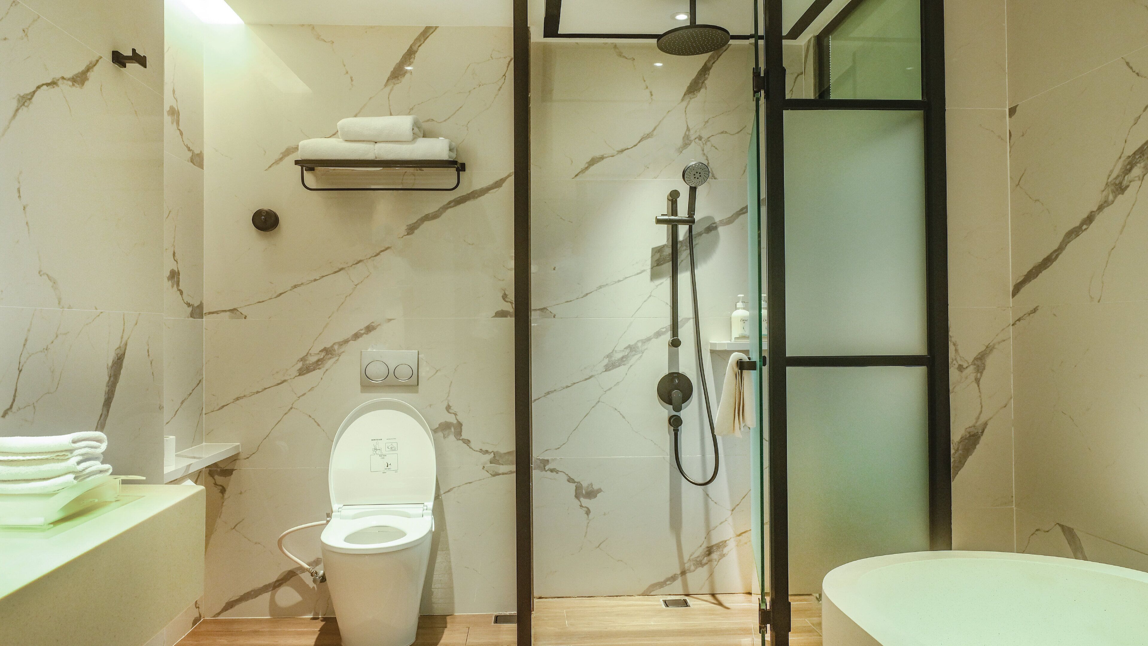 A modern bathroom with a toilet, shower, and sink.