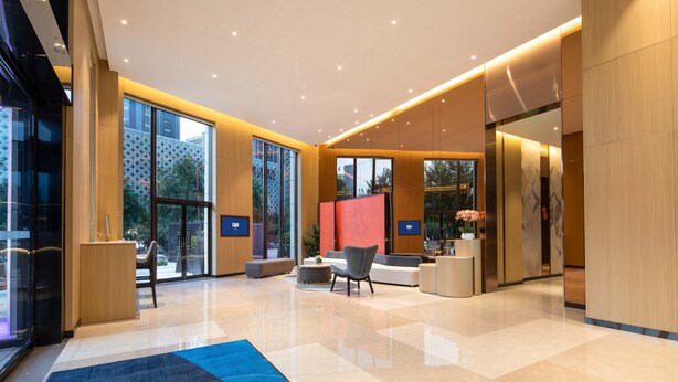 A modern lobby with a large seating area, a reception desk, and a glass wall offering a view of the outside. - Holiday Inn Express Xi'an High-tech South by IHG (Xi'an)
