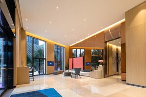 A modern lobby with a large seating area, a reception desk, and a glass wall offering a view of the outside. - Holiday Inn Express Xi'an High-tech South by IHG (Xi'an)