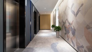 A modern hallway with a carpeted floor, a wooden door at the end, and two potted plants. - Holiday Inn Express Xi'an High-tech South by IHG (Xi'an)