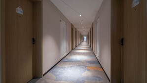 A long, narrow hotel corridor with wooden doors on both sides, numbered signs above each door, and a patterned carpet. - Holiday Inn Express Xi'an High-tech South by IHG (Xi'an)