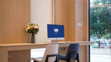 Un mostrador de recepción con un monitor de computadora, un florero con flores y dos sillas.