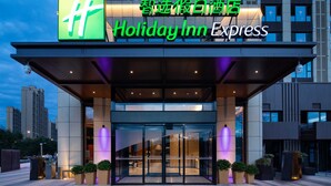 The exterior of a Holiday Inn Express hotel with a prominent green logo, large glass entrance doors, and a modern architectural design. - Holiday Inn Express Xi'an High-tech South by IHG (Xi'an)