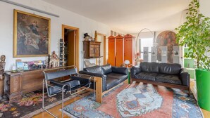 A living room with a black leather sofa, a wooden cabinet, and a large painting on the wall. - Palladio20 Loft & Terrace (Verona)