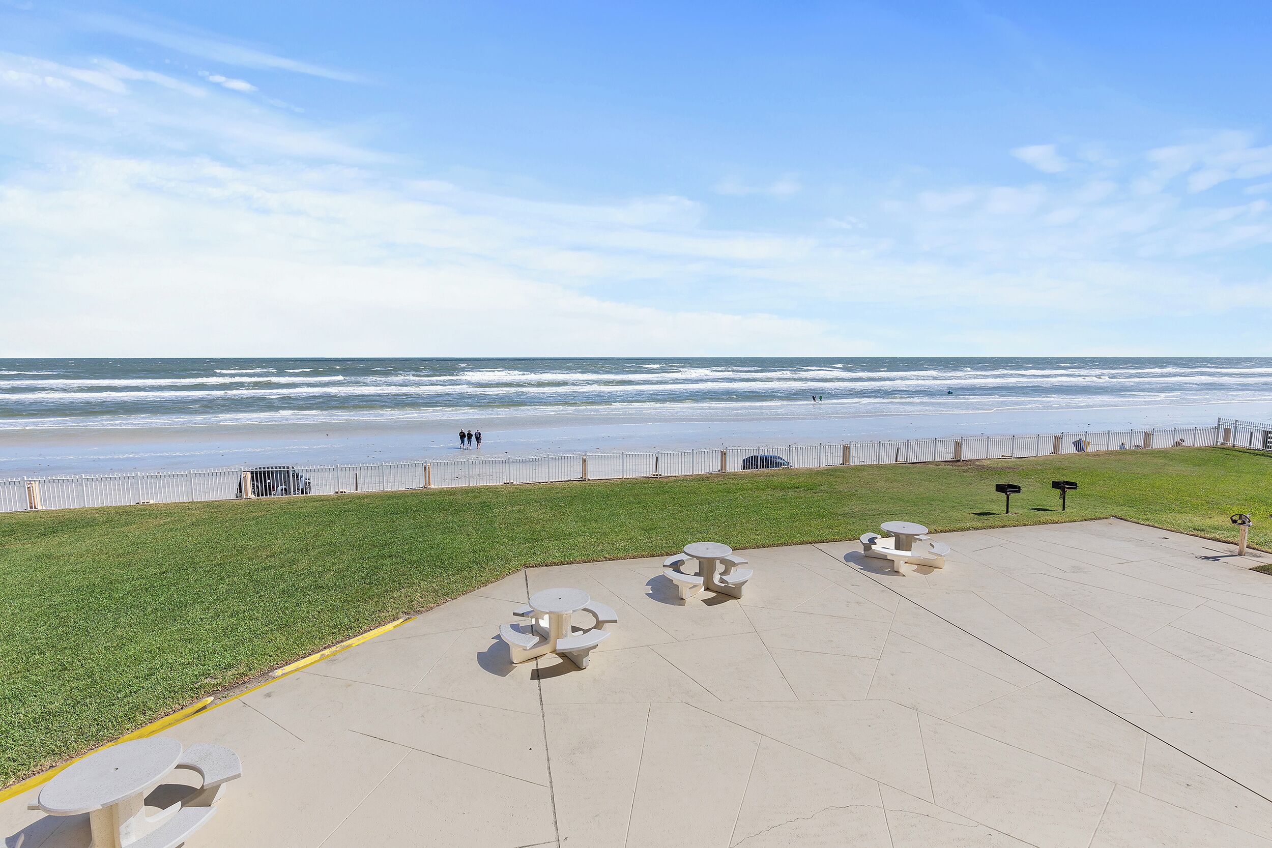 A beachside patio with picnic tables and a view of the ocean.