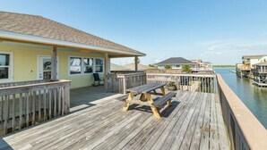 Eine Holzterrasse mit Picknicktisch und -stühlen mit Blick auf ein Gewässer und schwimmenden Strukturen.