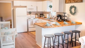 A modern kitchen with white cabinets, a wooden island with bar stools, and a 'Mise En Place' sign. - Clean, Private, Modern Farmhouse Style Home Close to Downtown! (North Charleston)