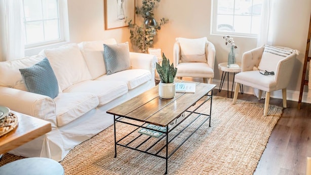 A modern living room with a white sofa, a coffee table, and two armchairs.