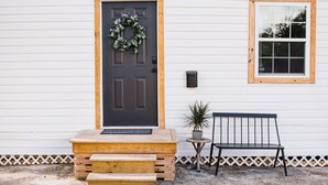 A front door with a wreath, a bench, and a small table with a plant.