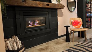 Ein modernes Wohnzimmer mit einem schwarzen Kamin, einer Holzbank, einem Sessel mit einem einzigartigen Kissen und einem Zebra-Muster Teppich.