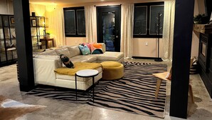 Ein modernes Wohnzimmer mit einer Eckcouch, einem Zebra-Teppich und einem kleinen runden Hocker.