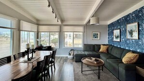 Una sala de estar moderna con comedor, ventanas amplias y pared con diseño azul.