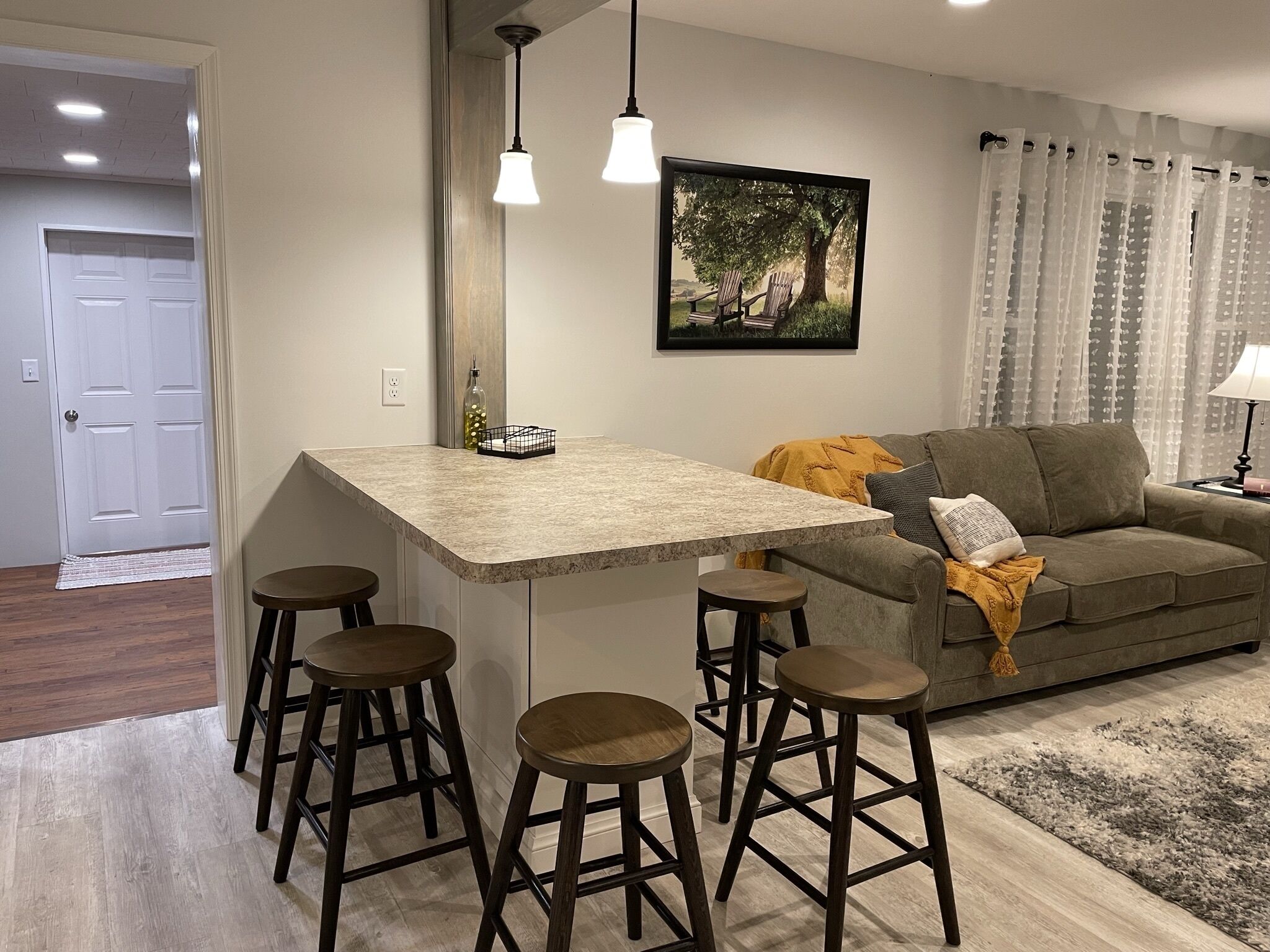 A modern kitchen with a bar area, a gray sofa, and a patterned rug.