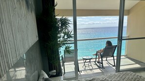A balcony with a view of the ocean, a chair, a small table, and a potted plant. - Beachfront PENTHOUSE - Best Views + 3-Beds + 2 Balconies + Maid Service (Cancún)