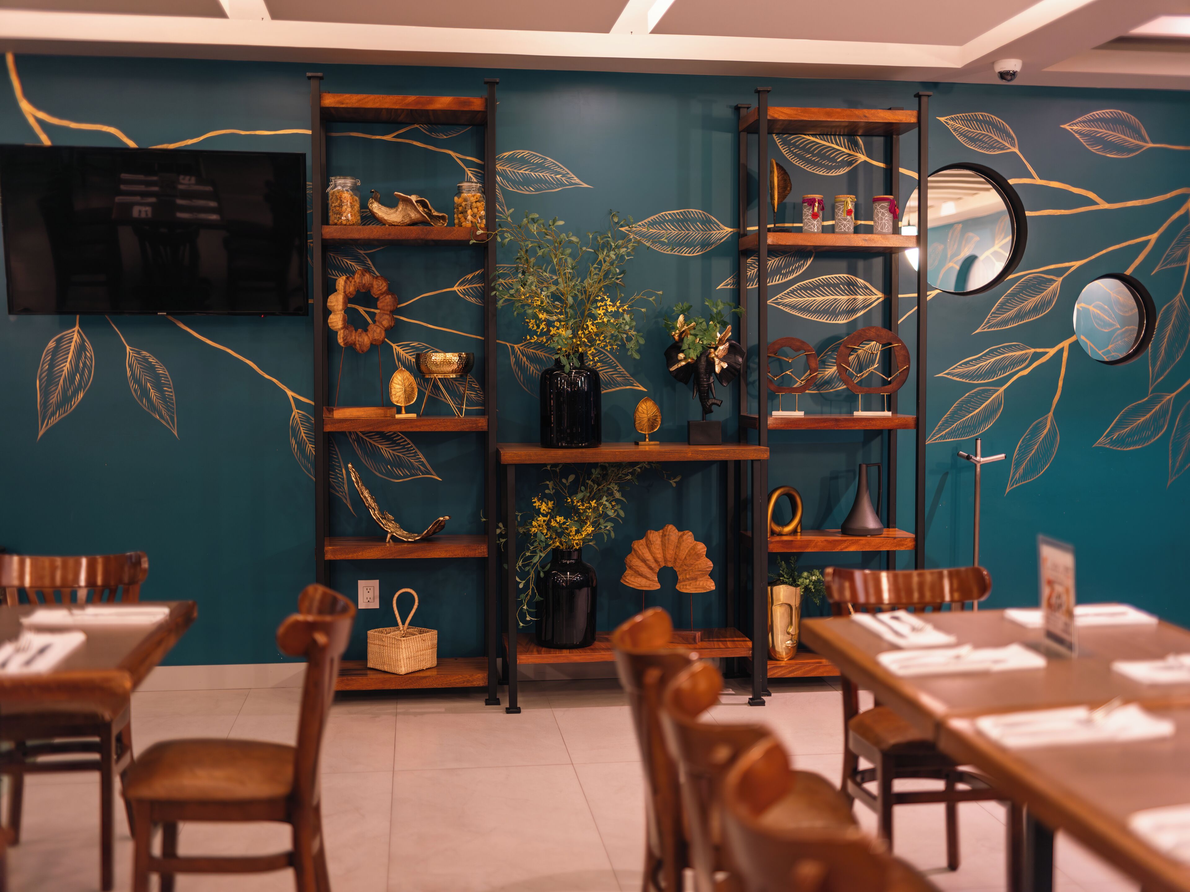 A restaurant with wooden furniture, teal walls, and decorative leaf patterns.