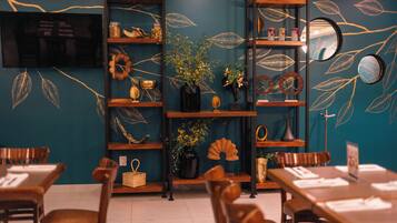 A restaurant with wooden furniture, teal walls, and decorative leaf patterns.