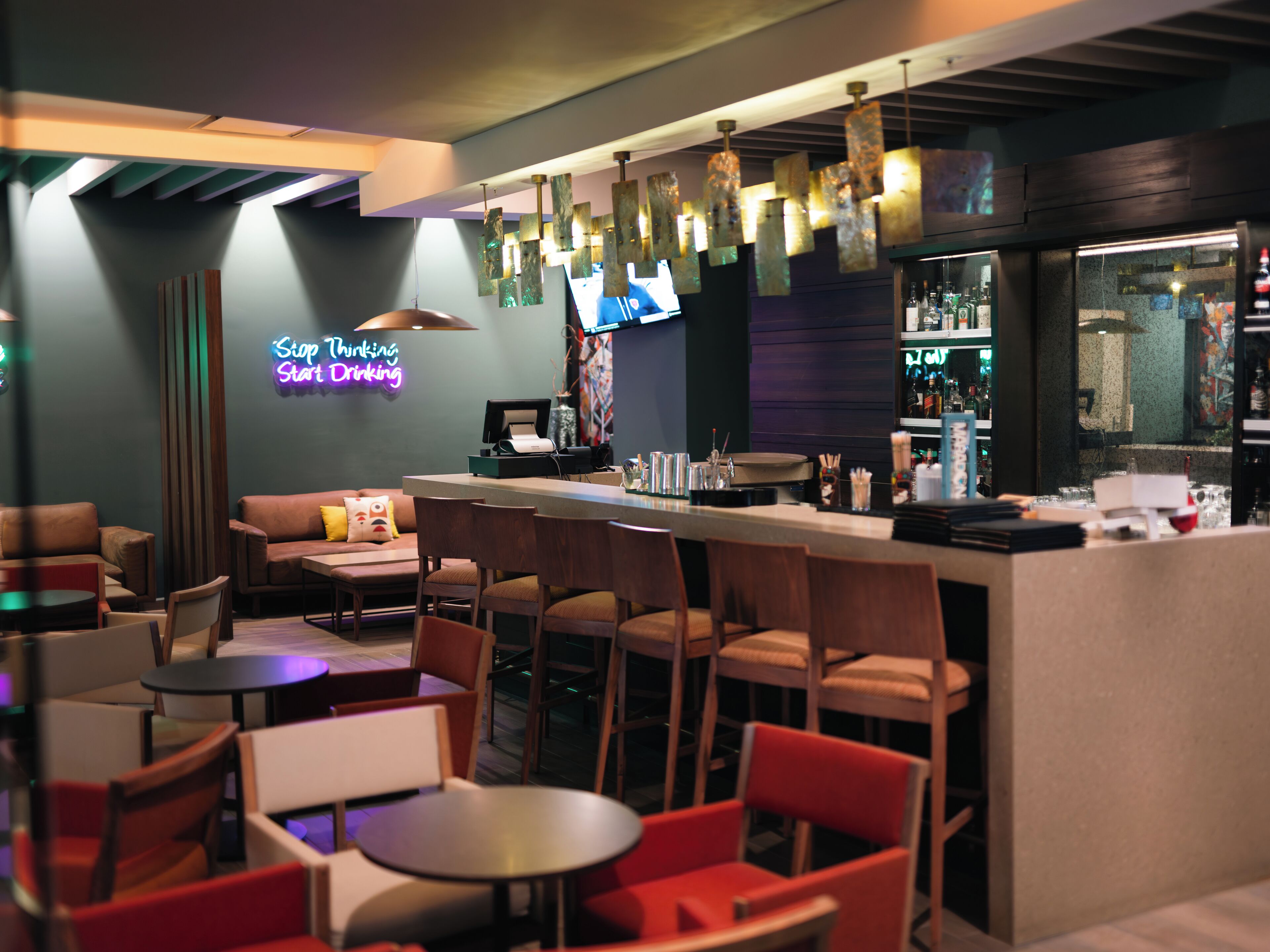 A bar area with seating, a neon sign, and a bar counter.
