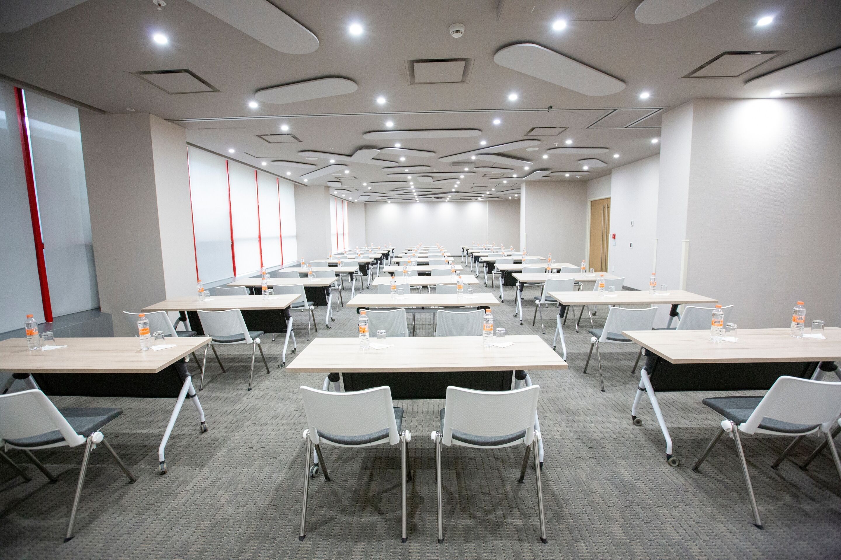 A conference room with multiple tables and chairs, equipped with water bottles and nameplates.