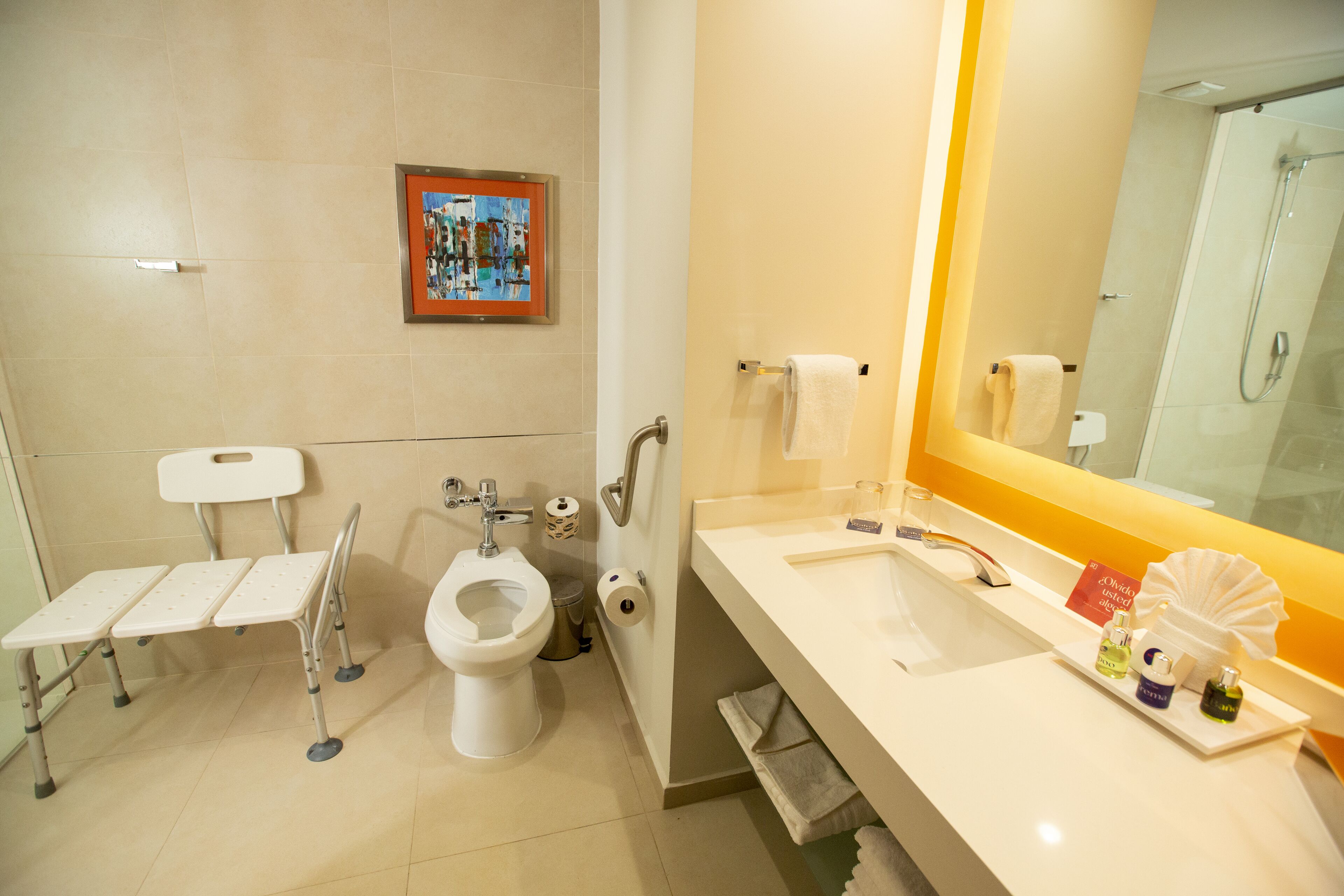 Ein Badezimmer mit Toilette, Bidet und Waschbecken. An der Wand hängt ein gerahmtes Bild und es gibt einen Handtuchhalter.