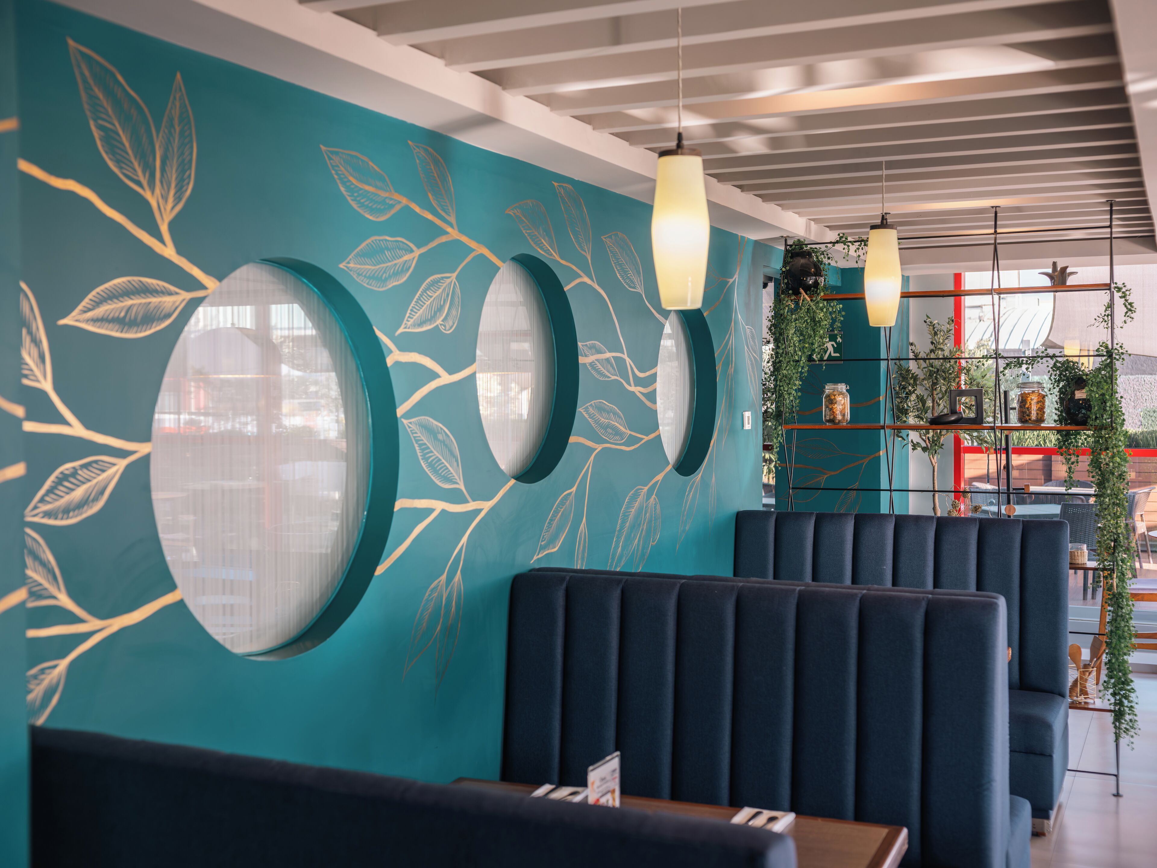 Interior moderno de restaurante com paredes verde-água, espelhos circulares e assentos em azul.