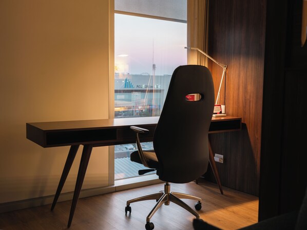 A modern office chair with wheels, a desk, and a lamp. - Metria Hotel (León)
