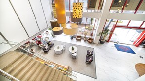 A spacious lobby with a high ceiling, multiple seating areas, and a staircase leading to an upper floor. - Metria Hotel  (León)