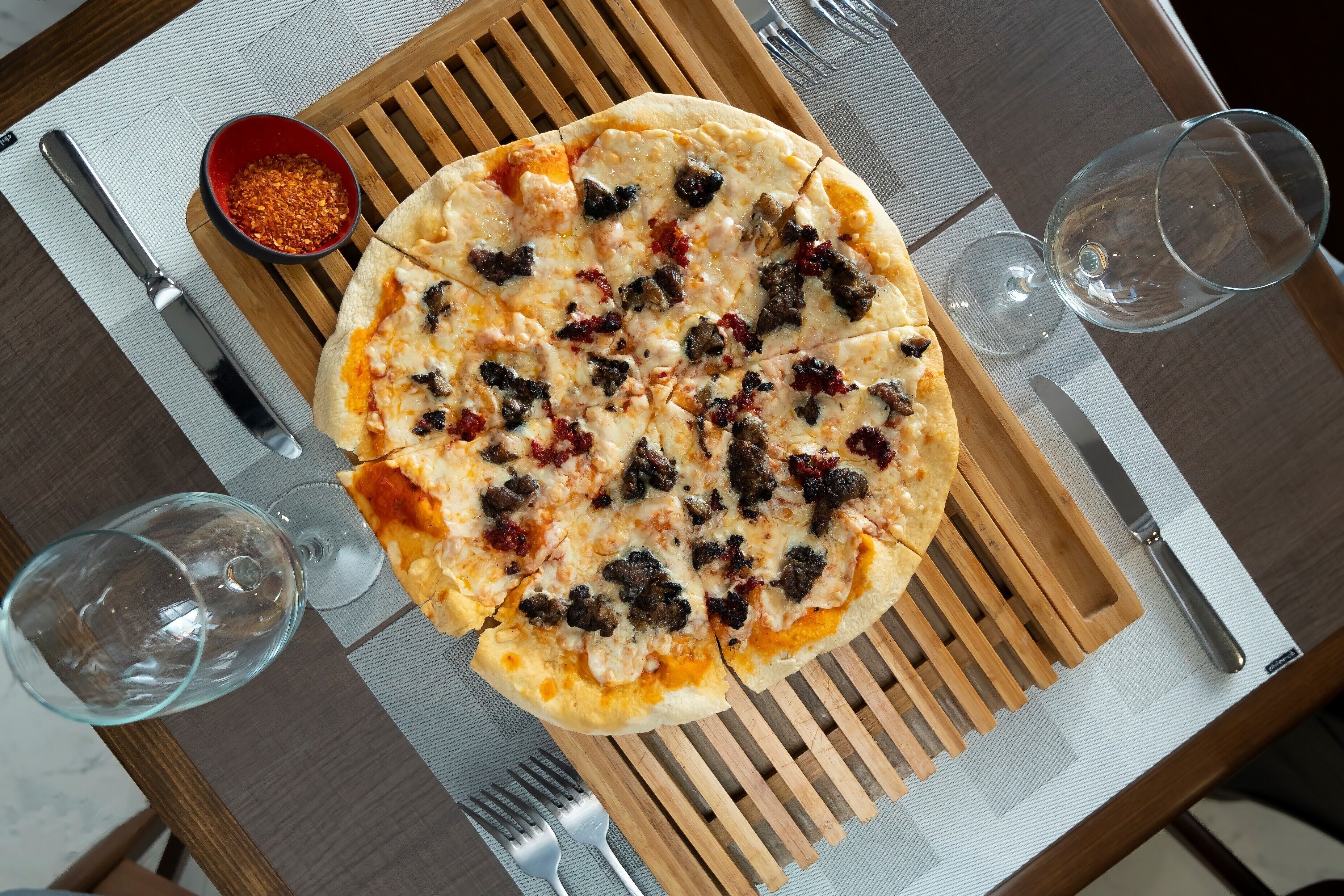 A pizza on a wooden board with a fork and knife beside it.