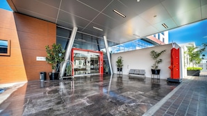 A modern building entrance with a glass door, potted plants, and a red sculpture. - Metria Hotel  (León)