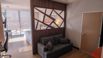 Habitación de hotel moderna con sofá, escritorio y vistas a la ciudad.