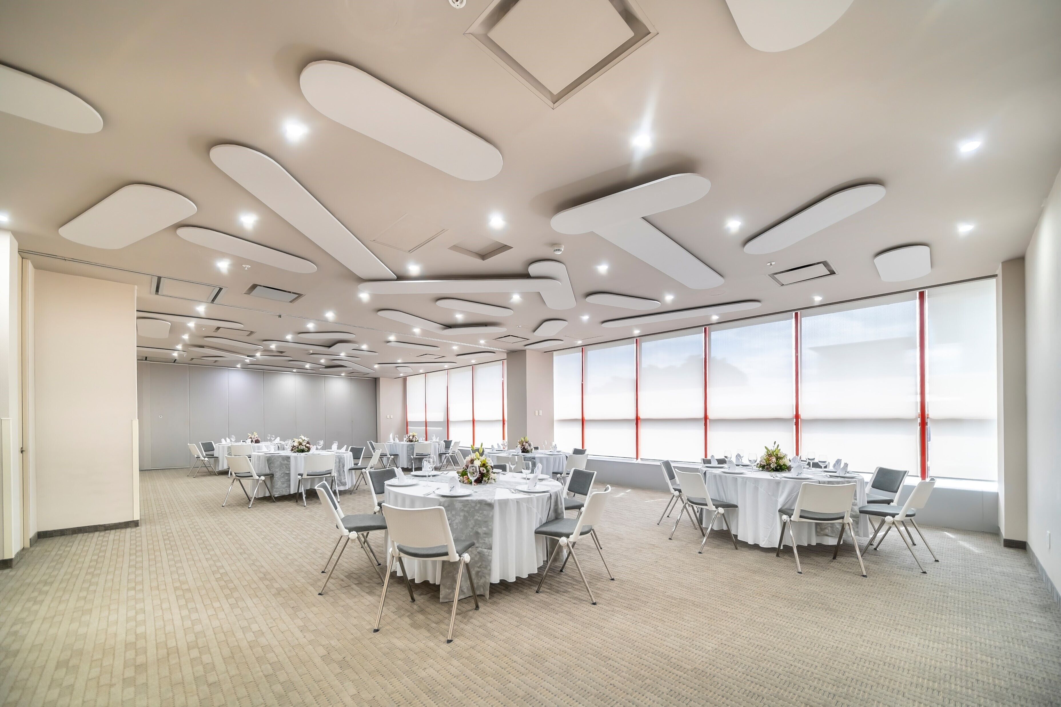 Une salle de conférence équipée de tables rondes, de chaises et de grandes fenêtres.