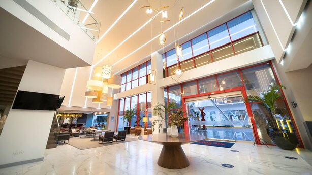 A spacious lobby with a high ceiling, modern lighting fixtures, and a central round table. - Metria Hotel  (León)