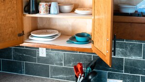 A kitchen with a wooden cabinet open, displaying dishes and utensils. - Grings Hill Guest House (Sinking Spring)
