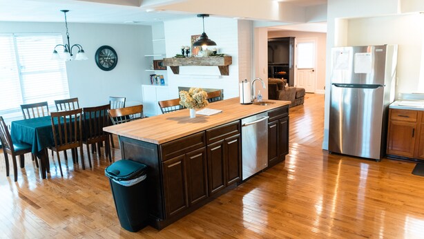 A modern kitchen with a wooden island, stainless steel appliances, and a dining area with a table and chairs. - Grings Hill Guest House (Sinking Spring)