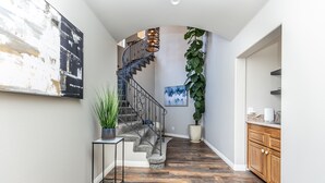Un pasillo con una escalera, una planta en maceta y un cuadro en la pared.
