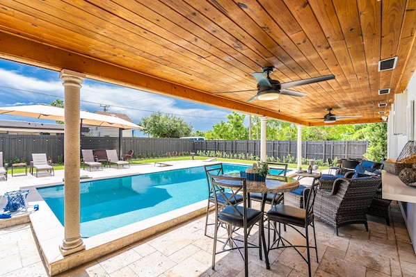 A covered outdoor area with a pool, patio furniture, and ceiling fans.