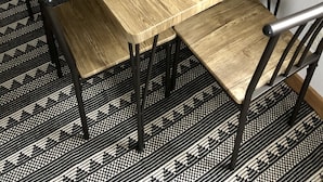 Een rechthoekige houten eettafel met een natuurlijke houtkleur, gecombineerd met zwarte metalen stoelen met een eenvoudig ontwerp.