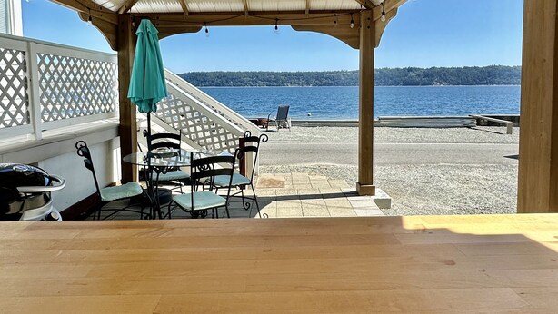 Un terrazzo in legno all'aperto con vista su una spiaggia e il mare.