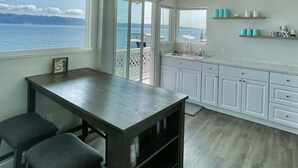 Cucina con vista sul mare, zona pranzo con tavolo e sedie, e un bancone con lavello.