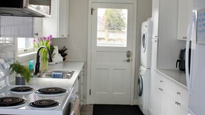 Een praktische keuken met witte kastjes, een fornuis, een magnetron en een wasmachine.