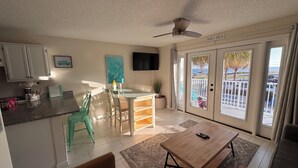 Un vaste espace de vie comprenant une table à manger, des chaises, un canapé et un balcon avec vue sur l’océan.