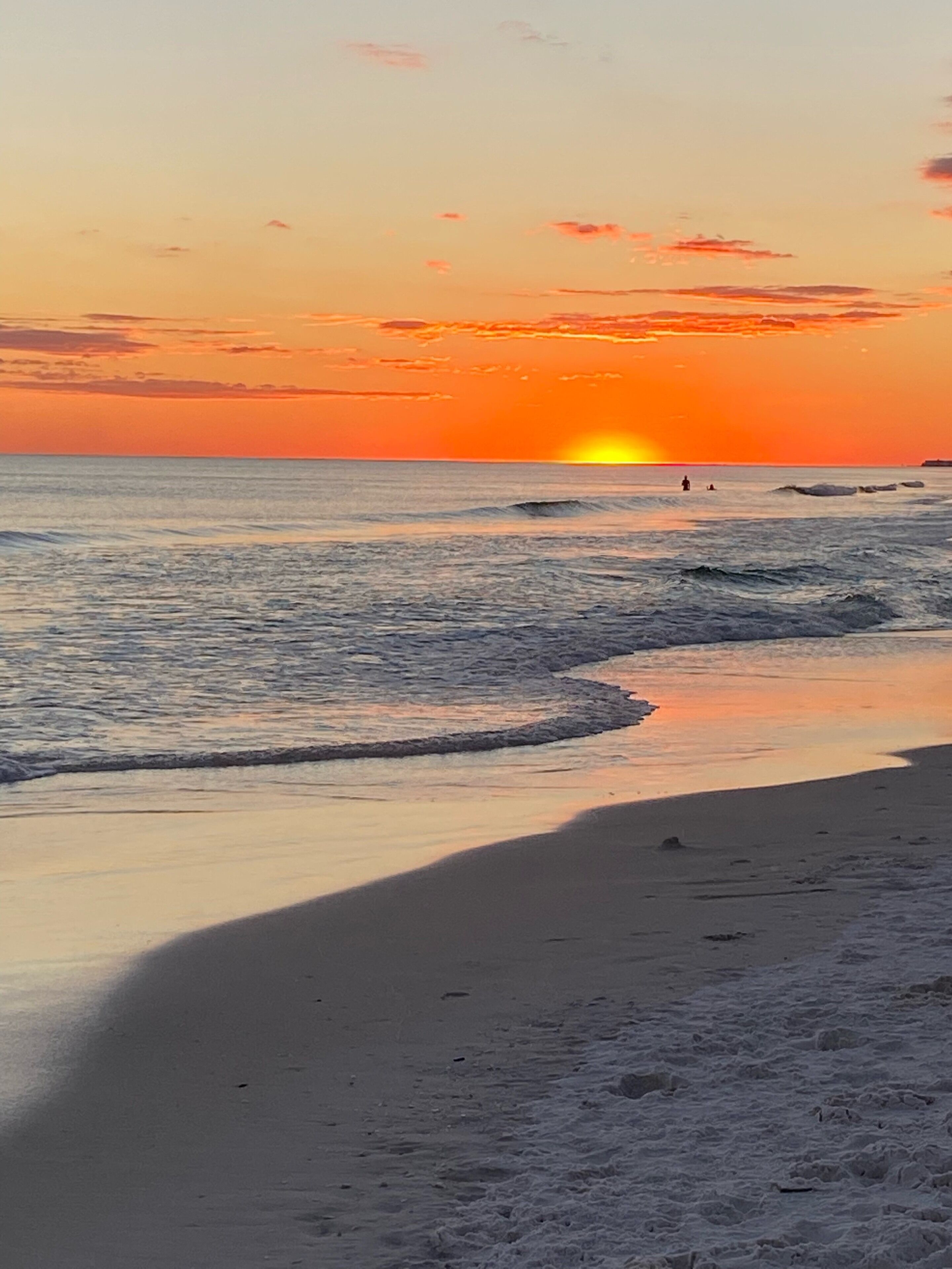 A beach at sunset with waves gently lapping the shore.