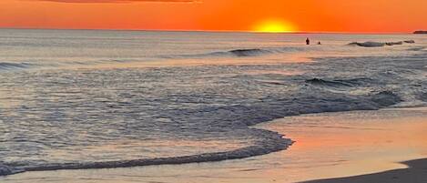 A beach at sunset with waves gently lapping the shore.