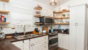 Una cocina moderna con armarios blancos, encimeras de madera, estufa de acero inoxidable y electrodomésticos integrados.