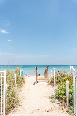 A sandy beach path leading to the ocean with a wooden walkway and white railings. - Nettles Island Beach Retreat . Golf Cart . Kayak . Private Beach Access (Jensen Beach)
